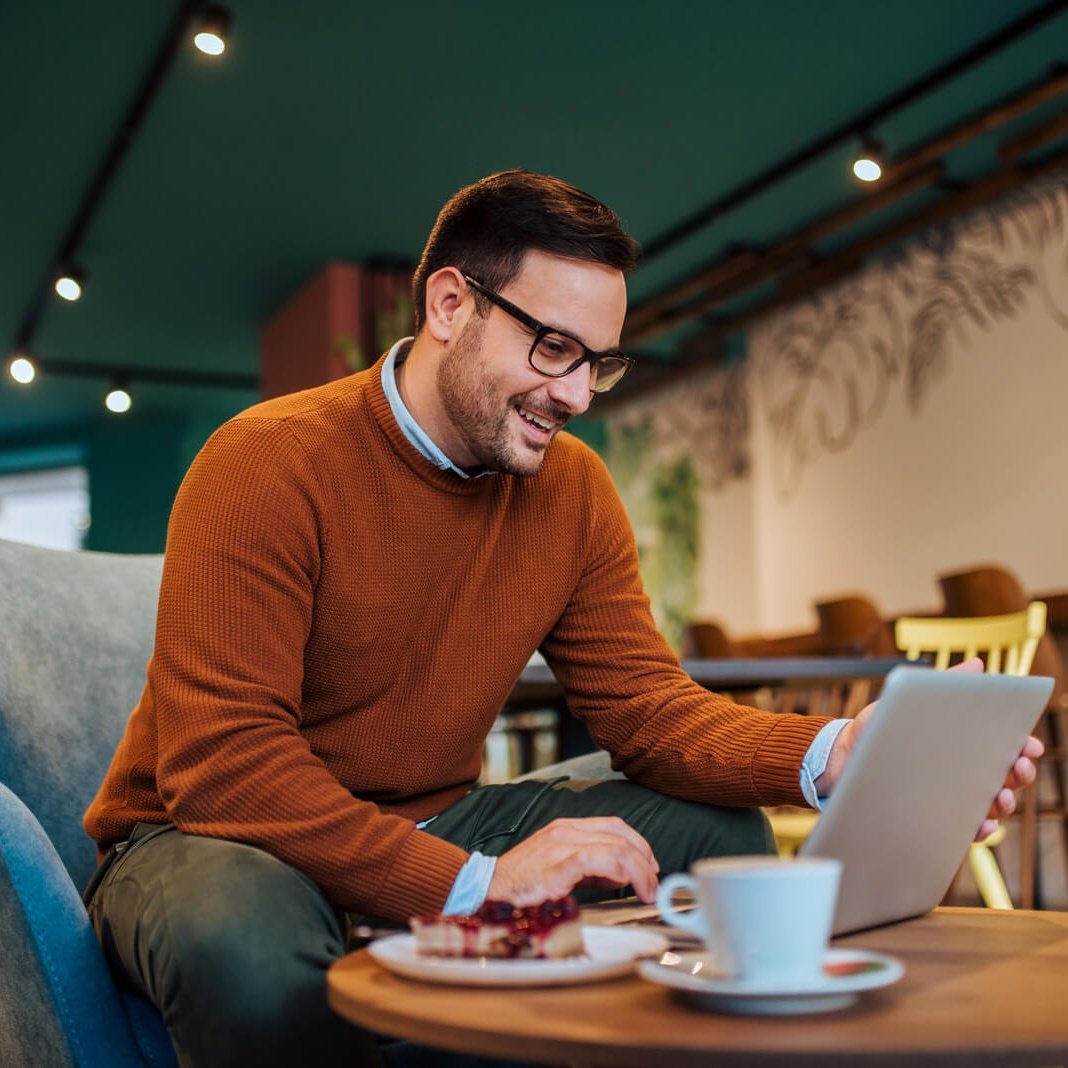 cheerful-man-using-laptop-in-a-cozy-restaurant-po-2024-10-18-07-51-26-utc-1-1-Cropped.jpg
